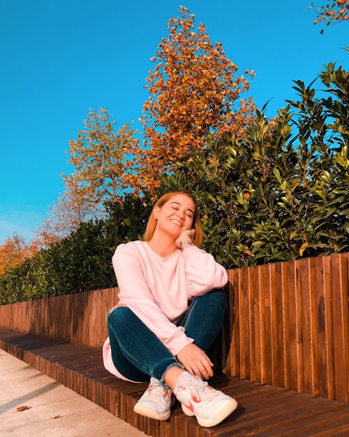 Woman in Pink Sweater Sitting on a Wooden Ground