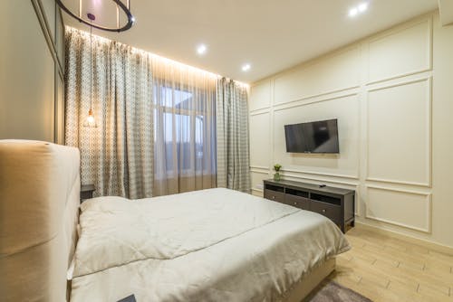 Modern bedroom equipped with TV set handing above nightstand