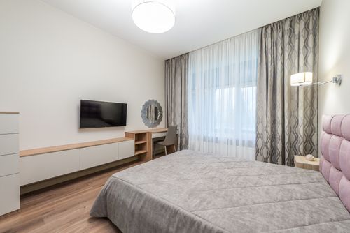 Free Interior of modern bedroom with TV set hanging near mirror with big bed near window Stock Photo