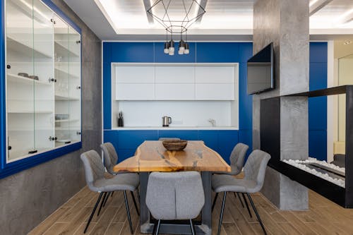 Interior of modern kitchen with cupboards and TV set with chairs placed around wooden table