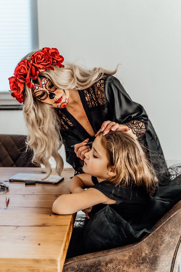 A Mother Applying Halloween Make-up On A Girl's Face
Sitting On A Chair