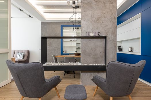 Modern design of studio apartment with comfortable armchairs placed near fireplace in kitchen with minimalist interior, free online jigsaw puzzle on JigsawPuzzlesFreeOnline.org