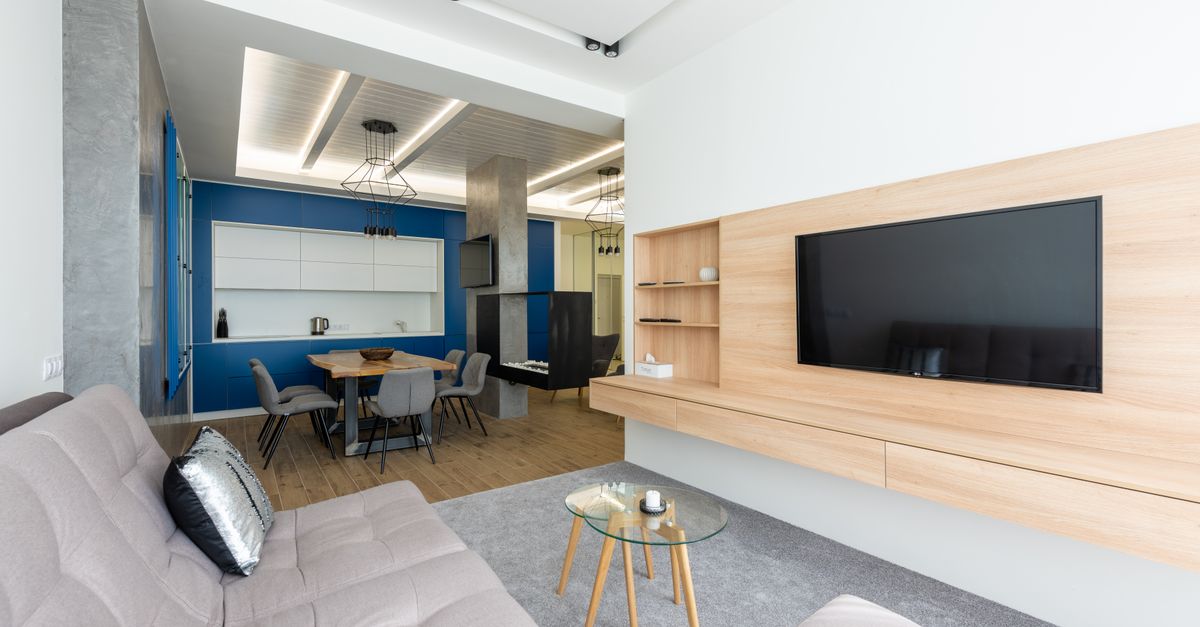 Helles, modernes Wohnzimmer mit offener KĂĽche und groĂźen Fenstern in einer energieeffizienten Wohnung.
