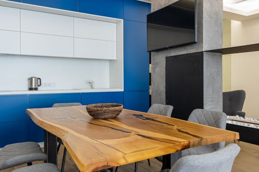 Sleek modern kitchen featuring a wooden table, blue cabinets, and contemporary decor.