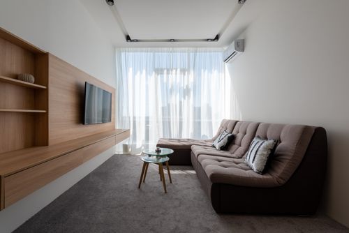 Free Comfortable couch with cushions near side tables against wall with wooden cupboard and modern TV in stylish living room with window Stock Photo