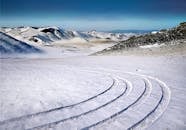 在蓝天下，俄罗斯白雪皑皑的山脉上有着清晰的轮胎痕迹