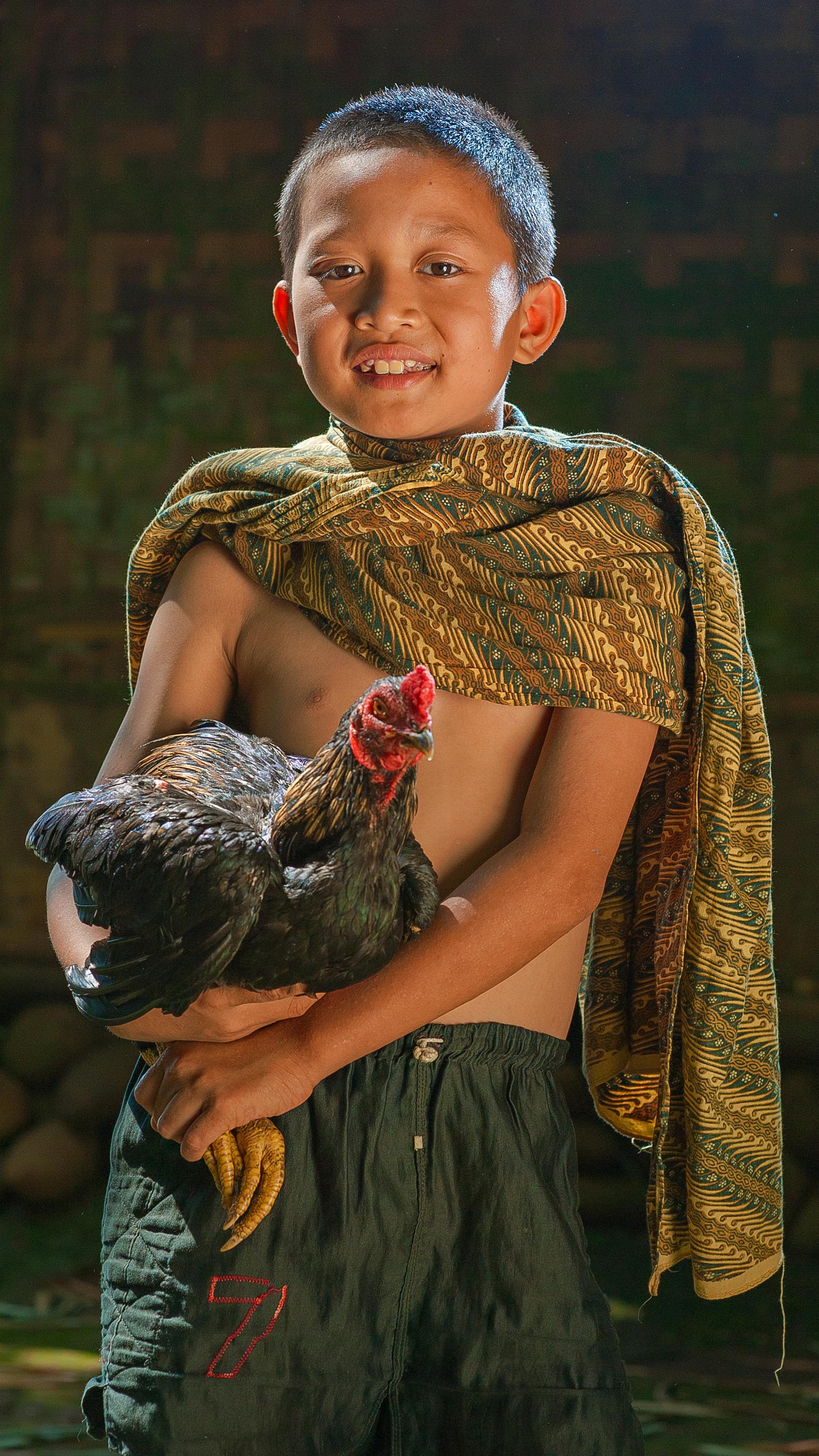 smiling ethnic boy with hen in countryside