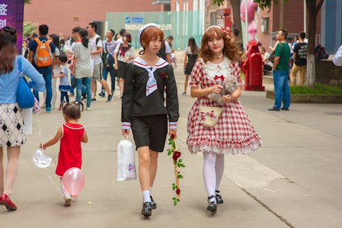 Asian girlfriends in retro wear walking on city street