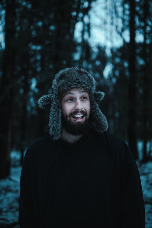 Free Man Wearing Winter Hat Standing Near Trees while Looking Afar Stock Photo