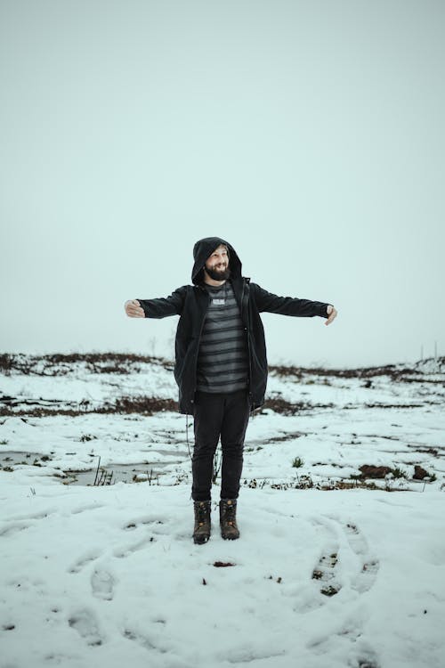 Man in Black Jacket Standing on Snow Covered Ground