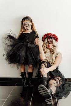 A mother and daughter in Day of the Dead makeup and costumes, posing indoors.