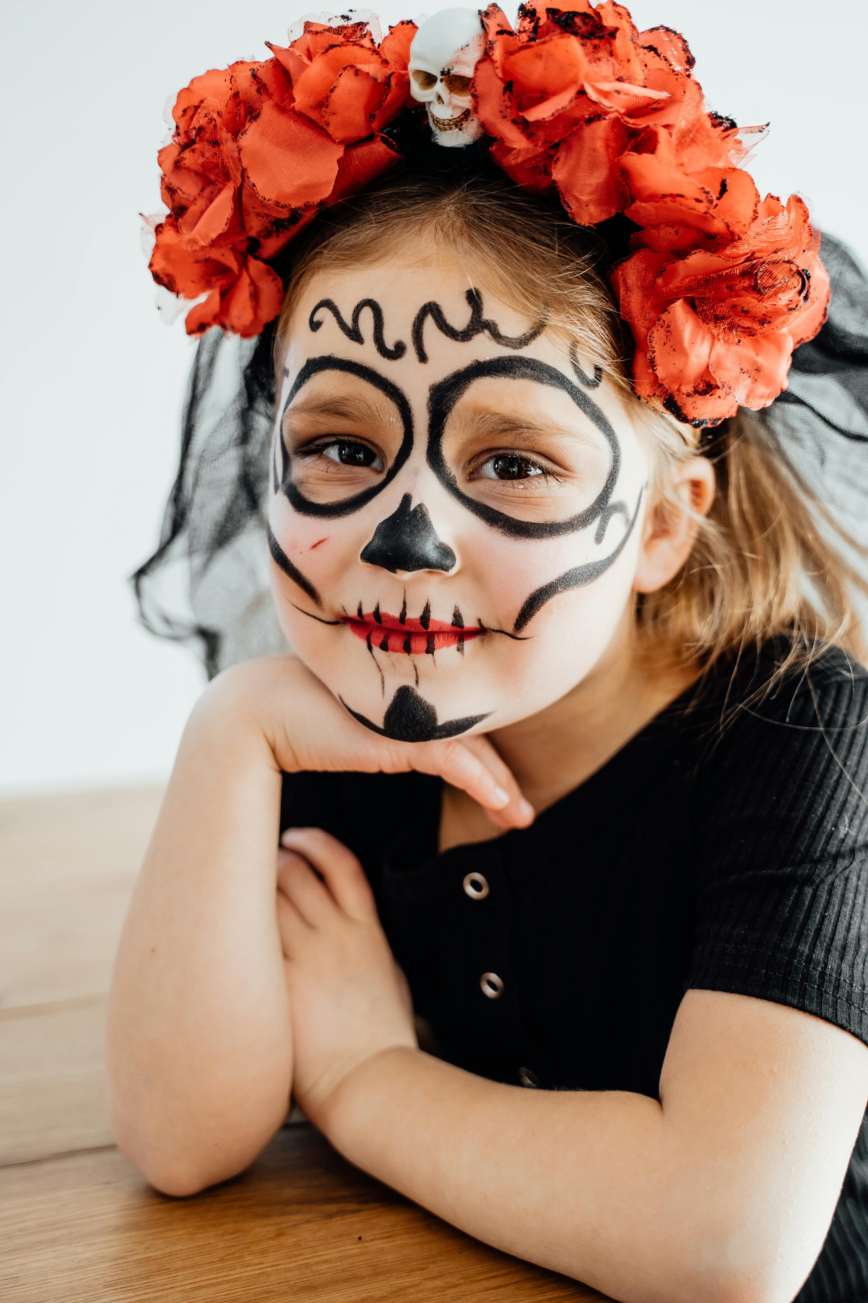 Free A young girl with creative Day of the Dead face paint and red rose headdress. Stock Photo