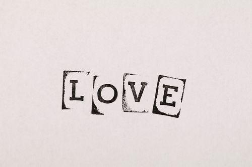 Free Minimalist art featuring the word 'LOVE' in black stencil font on a white background, ideal for inspiration. Stock Photo