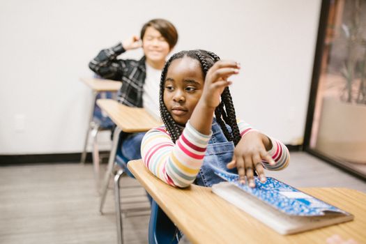 Young girl in classroom showing signs of bullying, highlighting school challenges.