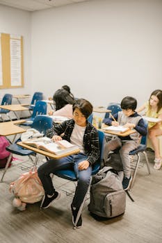 Group of students studying indoors in a classroom, focusing on learning and reading.