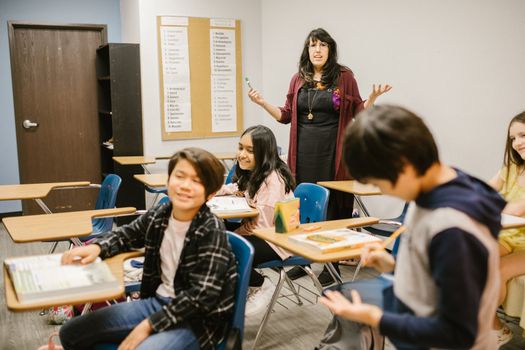 Students and teacher interacting in a lively classroom setting, promoting educational engagement. 6936010