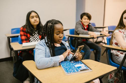 Free Students in a classroom using mobile phones, representing modern education. Stock Photo