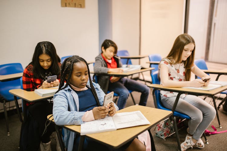 Students Sitting Inside The Classroom While Using Their Smartphone