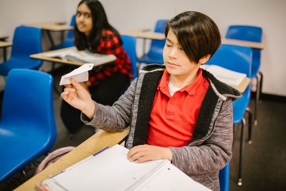 Photo by RDNE Stock project on Pexels Zwei Schüler in einem Klassenzimmer, einer mit einem Papierflieger, sitzen an Schreibtischen. - Foto von RDNE Stock-Projekt auf Pexels