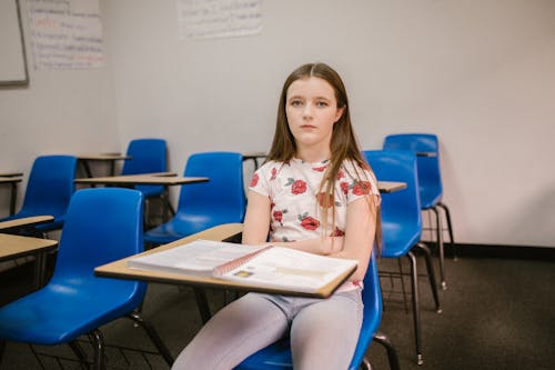 Free Girl Sitting on Her Desk Looking Lonely Stock Photo