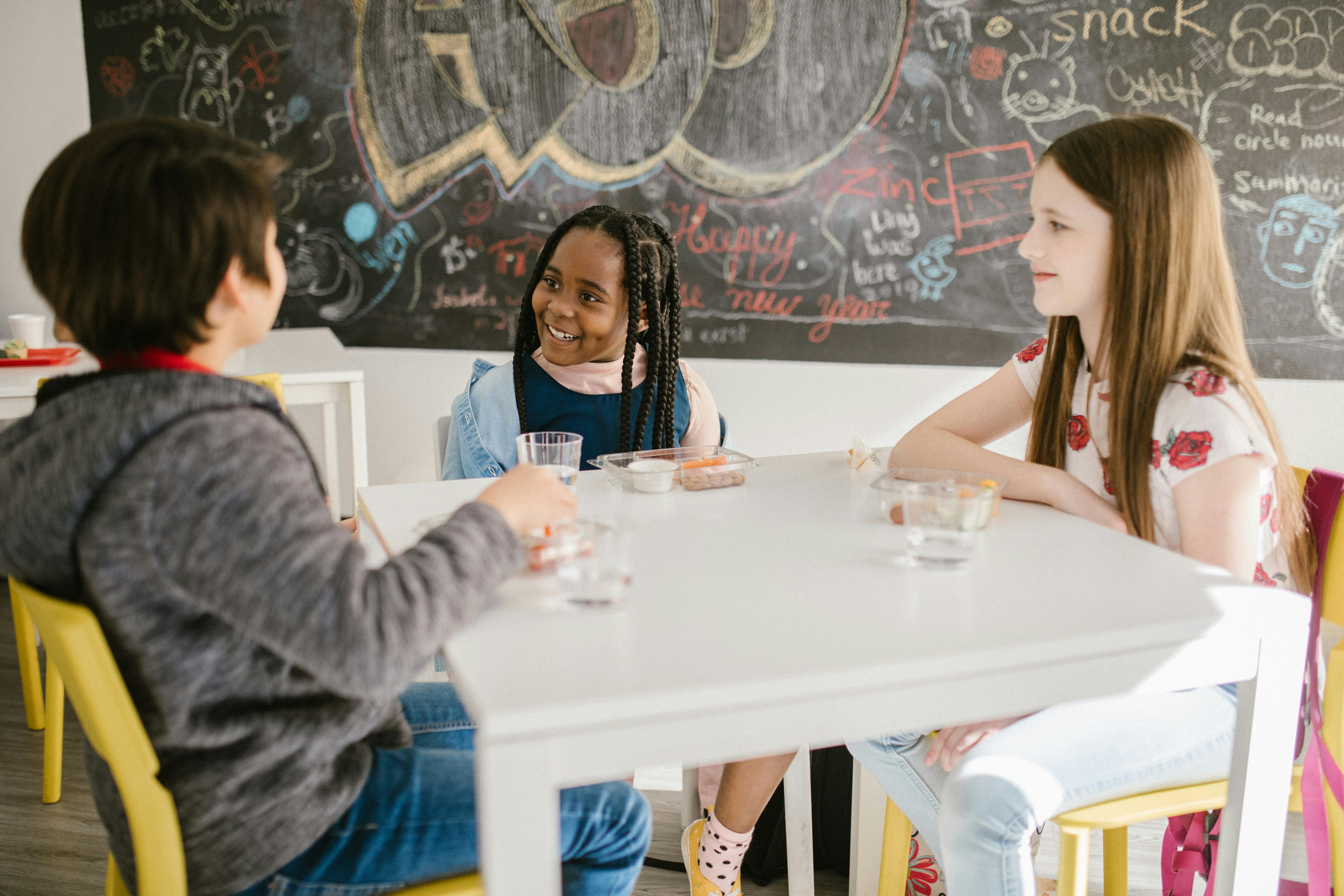 three students talking to one another inside the classroom