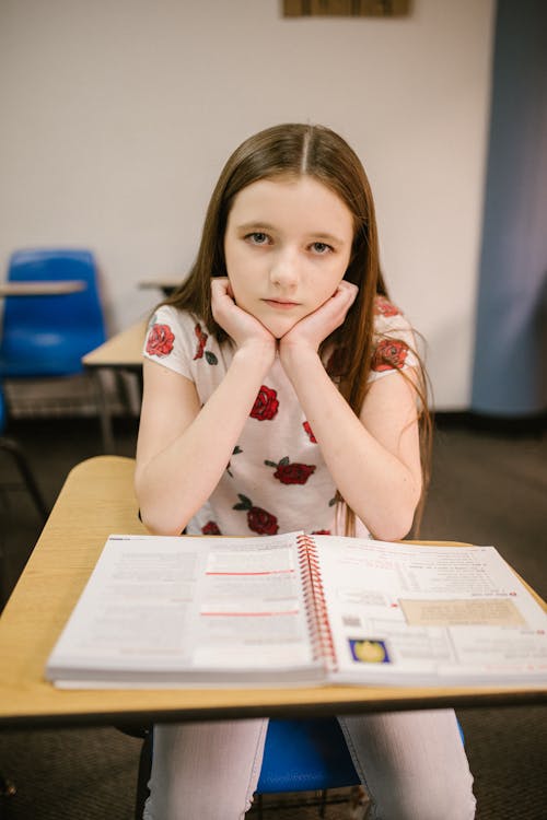 Free Girl Sitting on Her Desk Looking Lonely Stock Photo