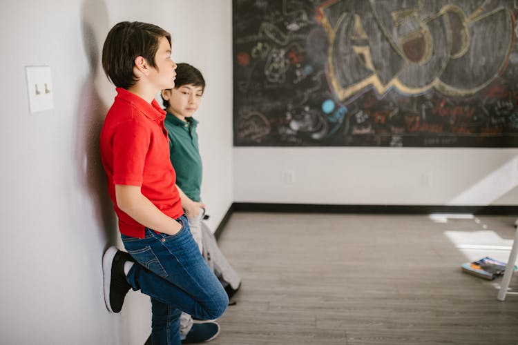 Two Boys Standing By The Wall Looking Arrogant