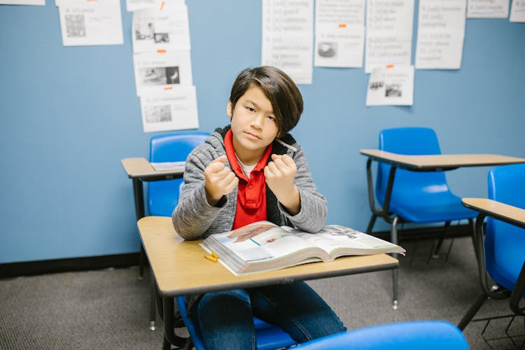 Boy Sitting On His Desk Looking Angry