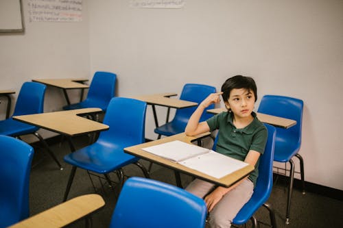Free Boy Sitting on His Desk Looking Lonely Stock Photo