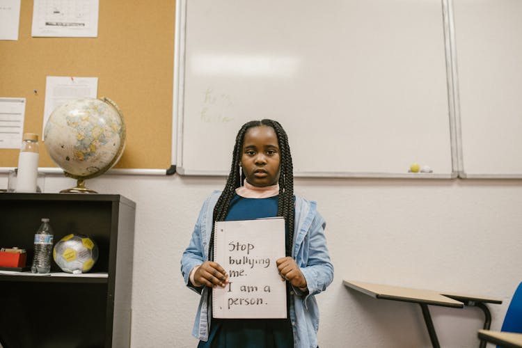 Girl Showing A Message Against Bullying Written In A Notebook