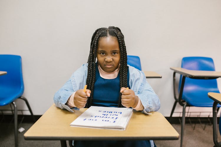 Girl Sitting On Her Desk Looking Angry