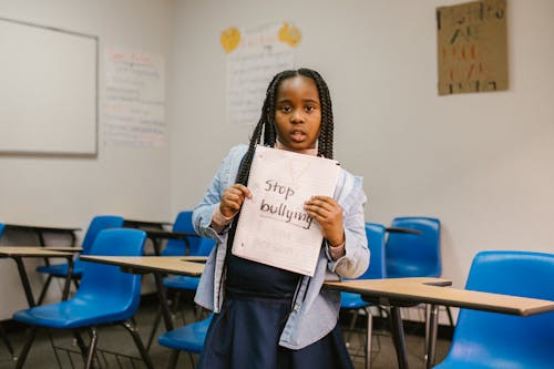 Free Girl Showing a Message Against Bullying Written in a Notebook Stock Photo