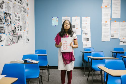 Girl Showing a Message Against Bullying Written in a Notebook