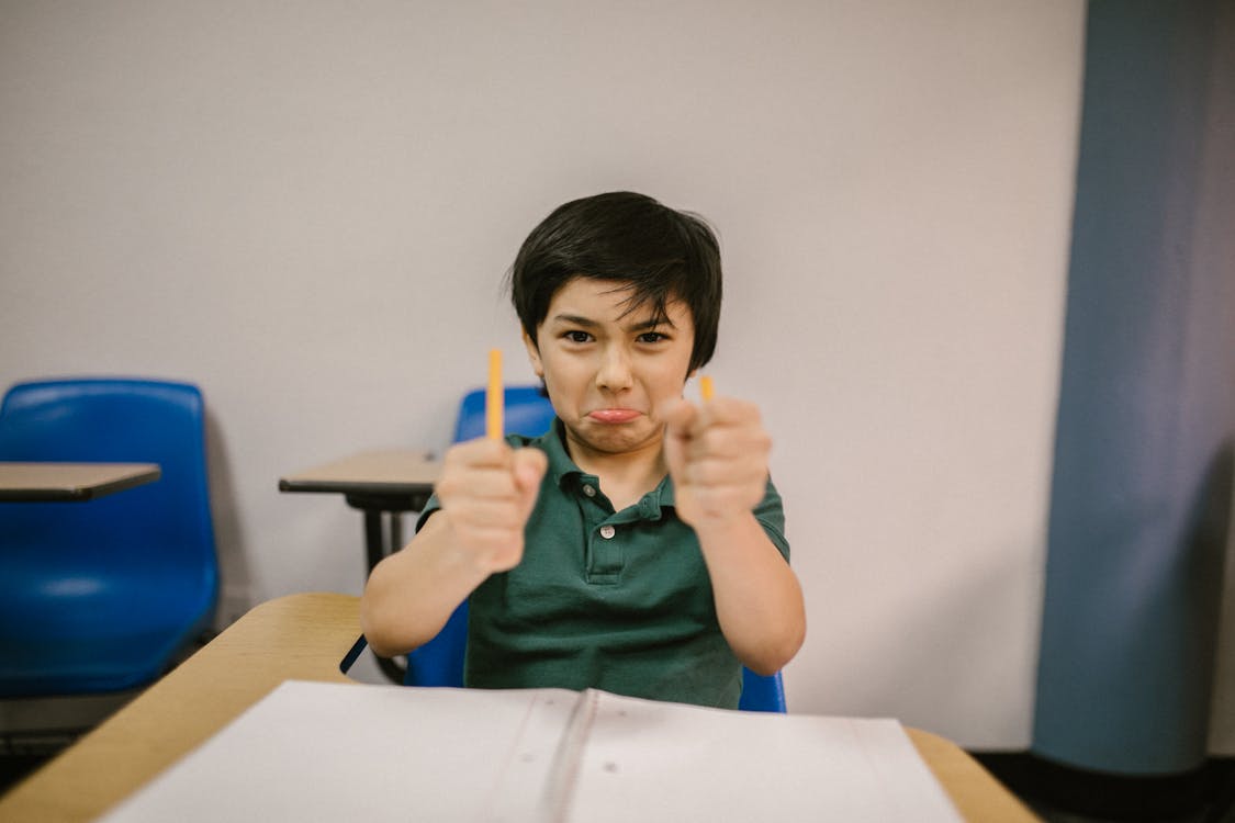 Free Boy Sitting on His Desk Looking Angry Stock Photo