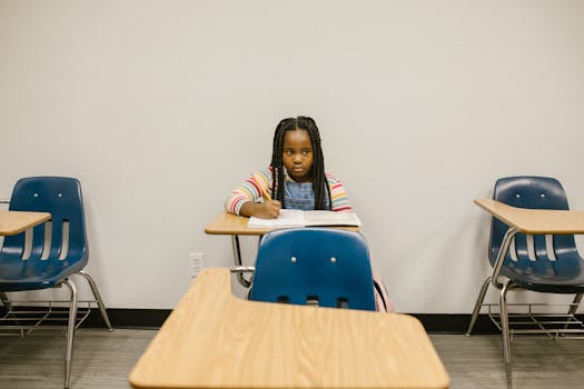 A young girl sits alone in a school classroom, symbolizing the impact of bullying.