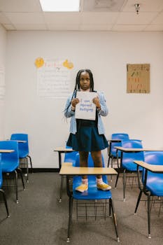 A child holds an anti-bullying sign in a classroom, promoting awareness.