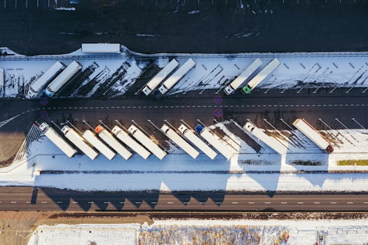Top-down aerial view of trucks parked in a snowy lot in Poznań, Poland, showcasing winter logistics.
