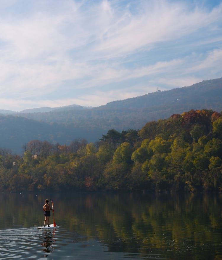 A Man Riding On A Paddleboard Floating On The Lake