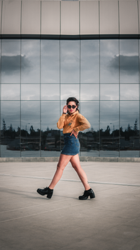 Stylish woman in denim and boots posing by a glass building in Peru.