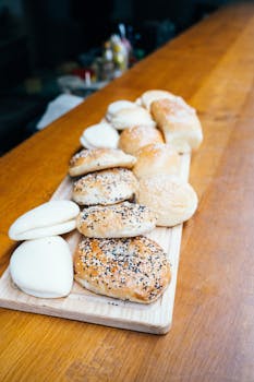 A variety of freshly baked bread rolls on a wooden board, perfect for a bakery display.