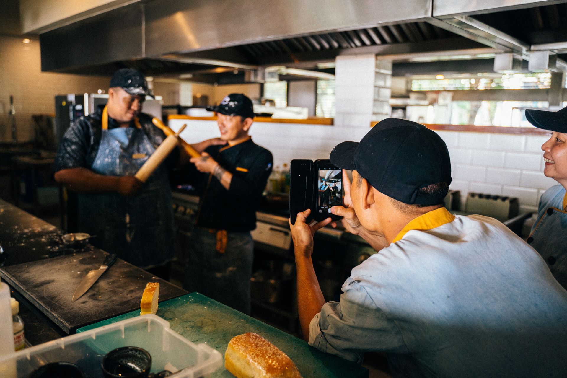 Chefs enjoy a playful moment during work in a vibrant restaurant kitchen.