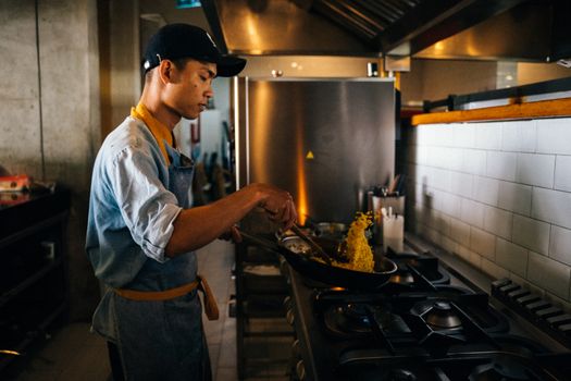 Chef tossing stir-fry in a professional kitchen, showcasing culinary skills and focus.