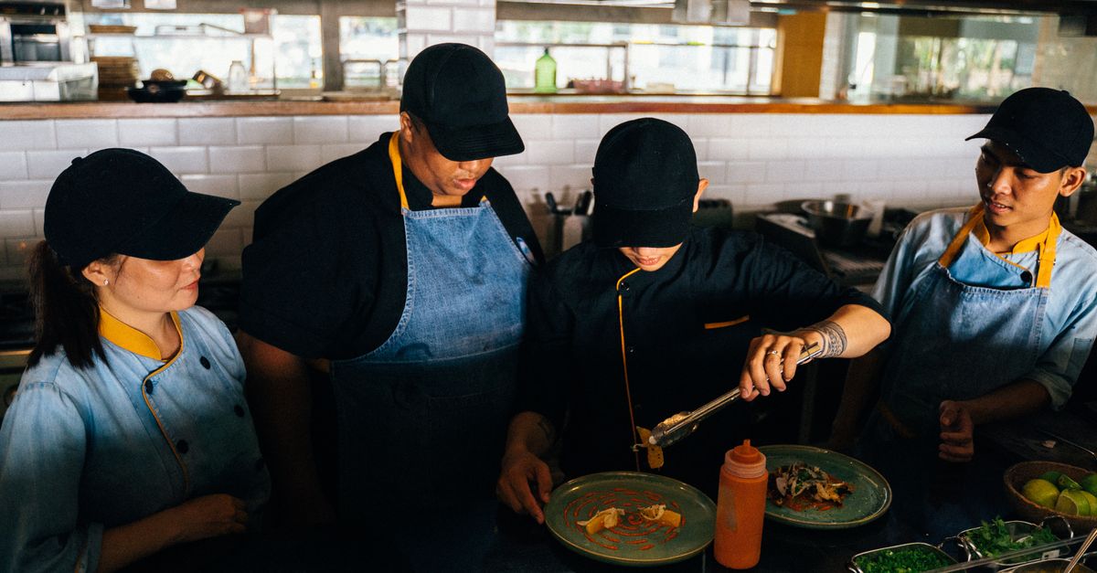 Chefs in a professional kitchen preparing and plating gourmet dishes with precision and teamwork.