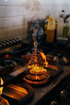 A blazing fire on a barbecue grill over a modern kitchen stove, showcasing cooking intensity.