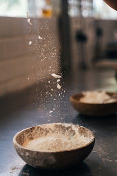 Flour being dusted into a wooden bowl, capturing a rustic kitchen scene with a touch of culinary artistry.