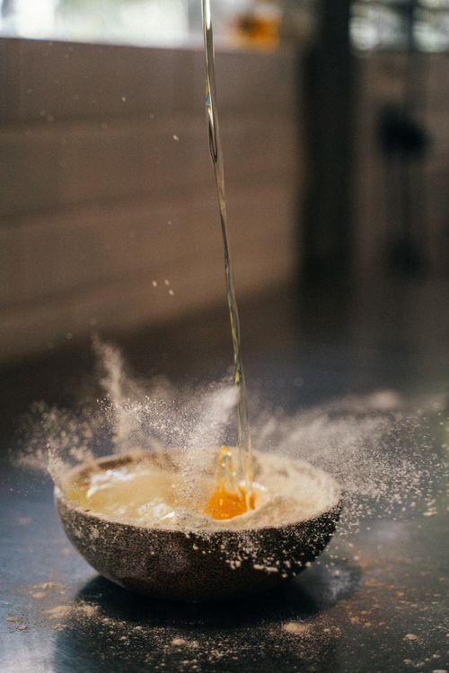 Free Capturing the moment of an egg being dropped into a flour-filled bowl, creating a splash in a kitchen setting. Stock Photo