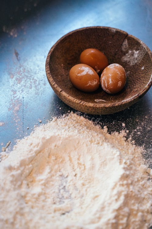 Free Close-Up Shot of Flour near Eggs in a Wooden Bowl Stock Photo