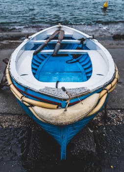 A close-up of a blue rowboat resting on a dock by the ocean shore, highlighting nautical themes.