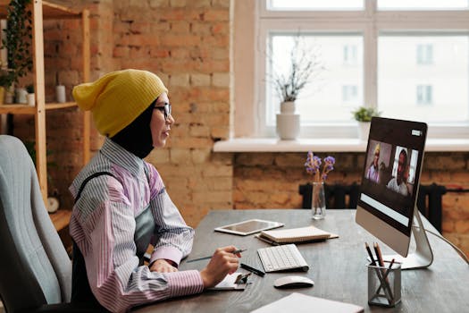 Businesswoman wearing casual attire participates in a video conference in a modern office setting.