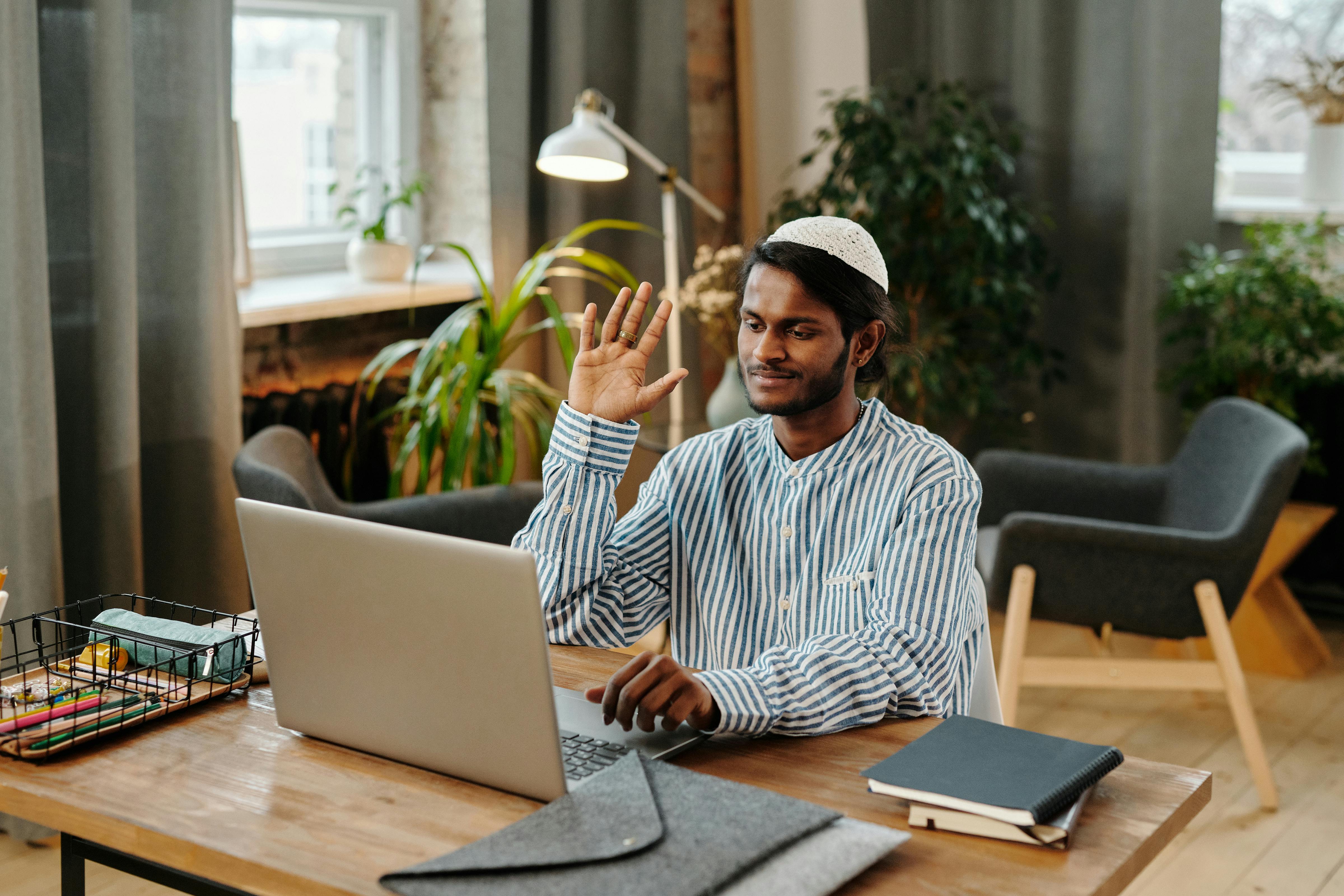 smiling man waving talking on video call on computer